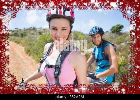 Fit couple cycling up mountain trail smiling at camera Stock Photo