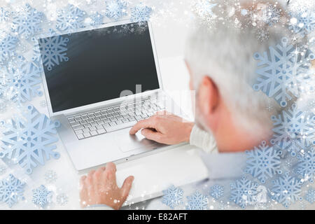 Closeup rear view of a grey haired man using laptop at desk Stock Photo