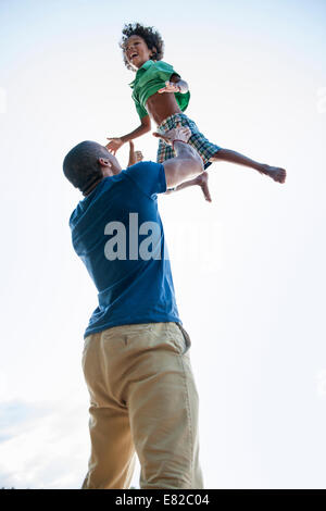 A man lifting a small boy up above his head in play. Stock Photo