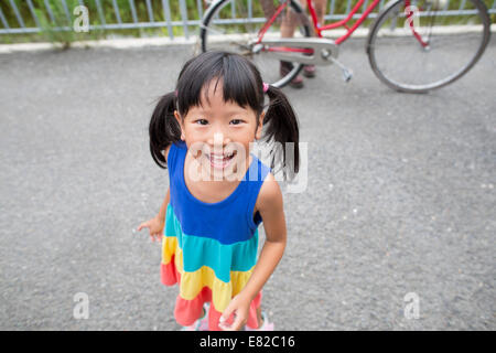 A young girl with pigtails smiling at the camera. Stock Photo