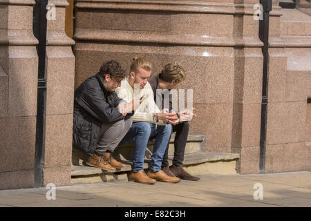 Three young men sitting on steps in a York street Stock Photo