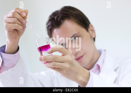 Scientist in a laboratory performing an experiment, mixing colorful test samples Stock Photo