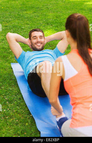 smiling man doing exercises on mat outdoors Stock Photo