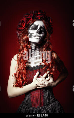 The sad young woman with muertos makeup (sugar skull) holding her chest Stock Photo