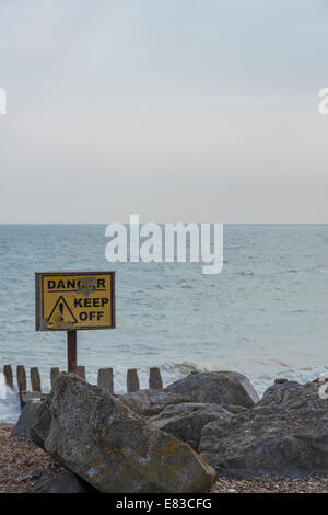 Danger Keep Off sign on rocks on the beach Stock Photo