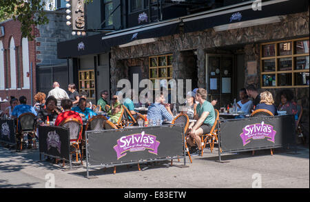 Patrons are served at the outdoor cafe of the famous Sylvia's restaurant on Lenox Avenue in the neighborhood of Harlem in NY Stock Photo