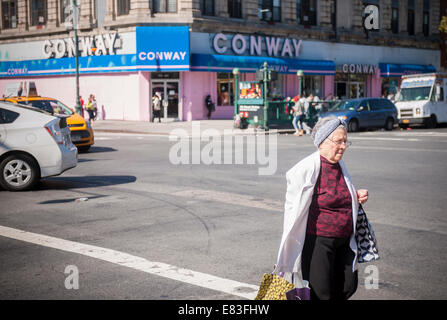 An elderly woman crosses the street in the New York neighborhood of Harlem Stock Photo