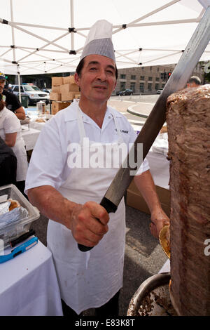 Turkish cook slicing Doner kebab meat from spit at an outdoor festival - USA Stock Photo