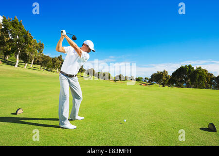 Golf player teeing off. Man hitting golf ball from tee box with driver. Stock Photo