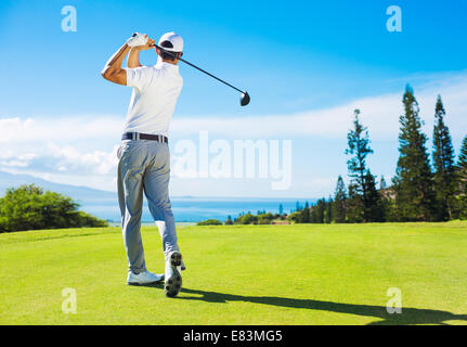 Golfer Hitting Ball with Club on Beautiful Golf Course Stock Photo