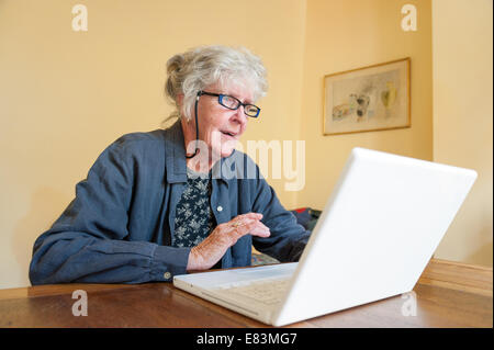 Elderly woman browsing Internet on AppIe laptop computer at home, UK Stock Photo