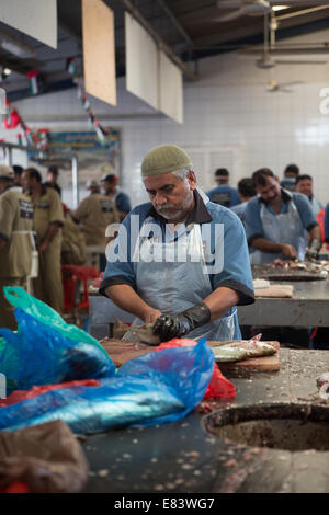 A middle-aged fish monger gutting fish at Deira Fish Market, Dubai, United Arab Emirates. Stock Photo