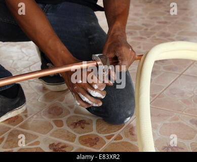 worker cutting a copper pipe with a pipe cutter Stock Photo