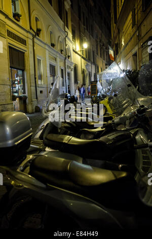 Series of mopeds and scooters parked at night in a Rome side street in the centre Stock Photo