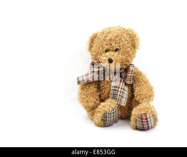 Teddy bear against a white background with plaid bow tie and plaid padded feet. Stock Photo