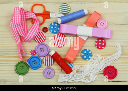 Colorful buttons, ribbon, thread, needles and scissors on wooden surface Stock Photo