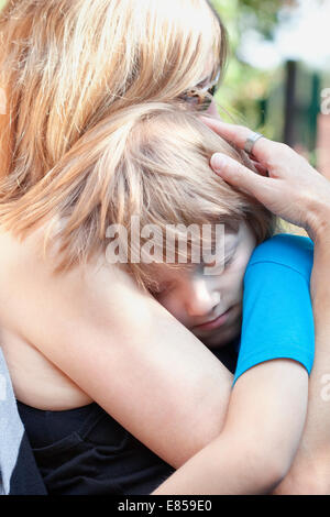 Boy Embracing his Mother, Sitting on her Lap Sleeping Stock Photo