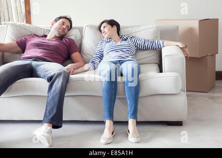 Couple relaxing on sofa while moving house Stock Photo