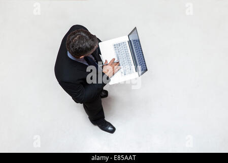 Businessman standing in lobby, using laptop computer Stock Photo