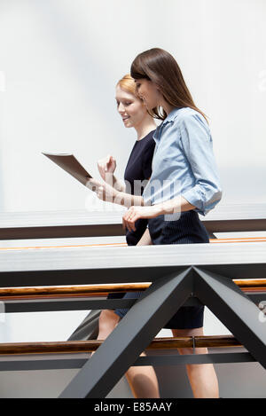 Colleagues walking in corridor and discussing file together Stock Photo