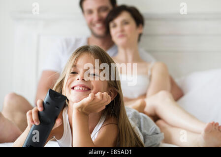 Little girl watching tv in bedroom with parents