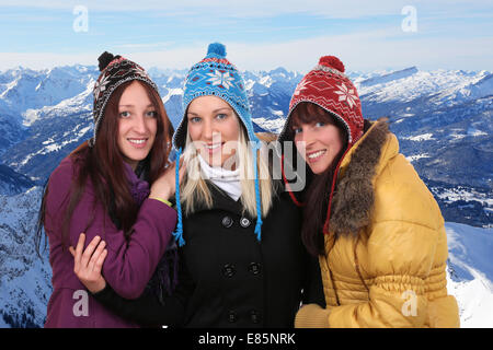 Group of smiling young women people in winter in the mountains with cap and scarf Stock Photo