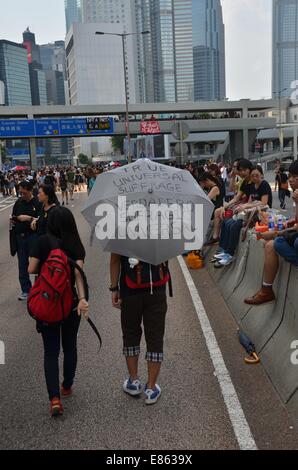 On Wednesday 1st October 2014, during a public holiday to mark the 65th anniversary of the founding of the People's Republic of China, a protester carries a slogan-bearing umbrella, as thousands of young people participate in the fourth day of the pro-democracy protest known as 'Occupy Central', blocking traffic on major roads in downtown Hong Kong. The mood continues to be calm and non-violent, whereas three days earlier, protestors faced tear gas and pepper spray from police in full riot gear. Credit:  Stefan Irvine/Alamy Live News Stock Photo