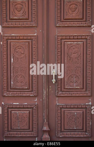 Wooden church door with carved religious symbols. Angels and cross motif. Stock Photo
