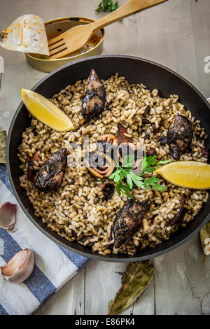 rice with squid on ink sauce on pan Stock Photo