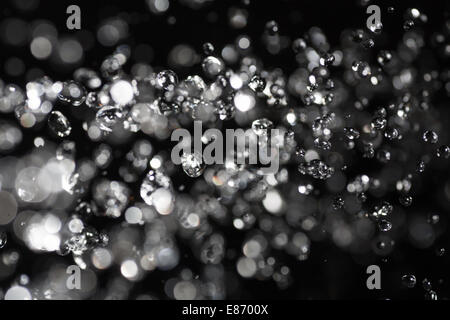 water drops fly in the air with defocused lights on background Stock Photo