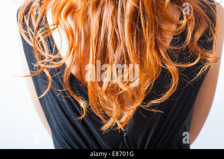 rear closeup view of the shoulders of red haired (carrot-top) female weared black dress Stock Photo