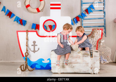 Two little girls play with seashells, sea theme. Stock Photo