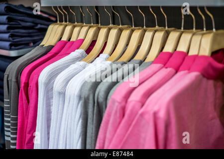 Fashionable clothing on hangers in shop Stock Photo