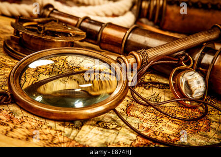 Vintage magnifying glass, compass, telescope and a pocket watch lying on an old map. Stock Photo