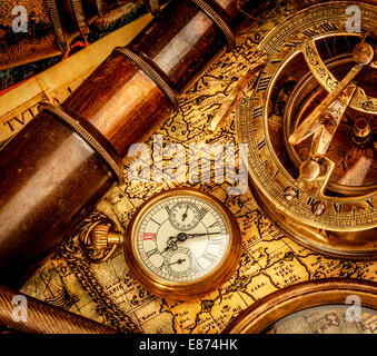 Vintage magnifying glass, compass, telescope and a pocket watch lying on an old map. Stock Photo