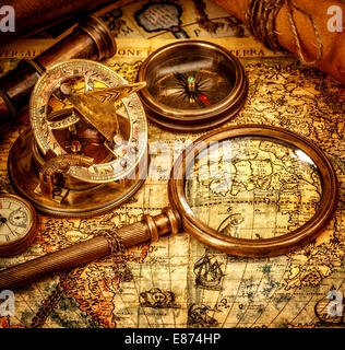 Vintage magnifying glass, compass, telescope and a pocket watch lying on an old map. Stock Photo