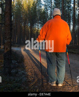 Elderly senior woman standing in the forest with nordic walking poles , Finland