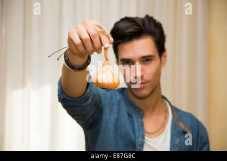 Smiling young man holding a fresh onion in his hand in a healthy diet and lifestyle or vegetarian concept Stock Photo