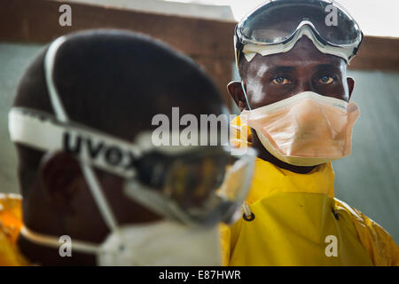 The team in charge of burning the bodies of Ebola victims dress in PPE before transporting the bodies from a truck to the incine Stock Photo