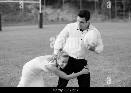 Trash the dress, bride and groom playing rugby Stock Photo