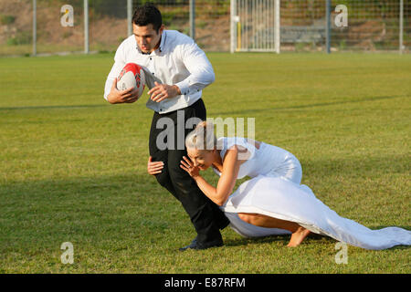 Trash the dress, bride and groom playing rugby, bride tackling the groom Stock Photo