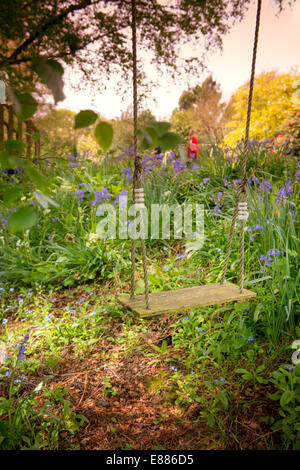 A traditional wood and rope swing hangs from a tree in an East Sussex country garden. Stock Photo