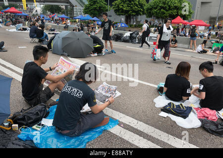 Hong Kong, China. 2nd October, 2014.   Students and other supporters of the Occupy Central movement congregating around the government offices area at Tamar. All the roads in the area are blocked from traffic and public transport. Printed newspapers are still being read by the activists. Credit:  Kees Metselaar/Alamy Live News Stock Photo
