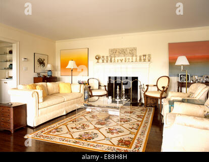 Cream sofas on either side of large floral patterned rug on floor of modern living room Stock Photo