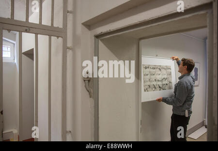 Michael Kirsten hangs a picture in the art exhibition 'so nah. weit fern: Bilder aus der Hafterfahrung' (So near.far away: pictures of the prison experience) at the memorial site Andreasstrasse in Erfurt, Germany, 2 October, 2014. The exhibition displays artwork from former prisoners at the former Stasi prison until 13 January, 2015. Photo: Michael Reichel/dpa Stock Photo