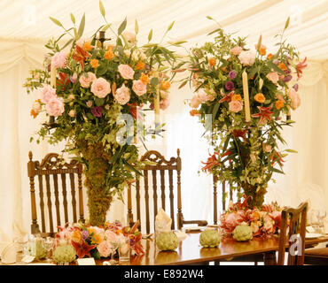 Pink roses in sumptuous floral arrangements on table in marquee decorated for a wedding