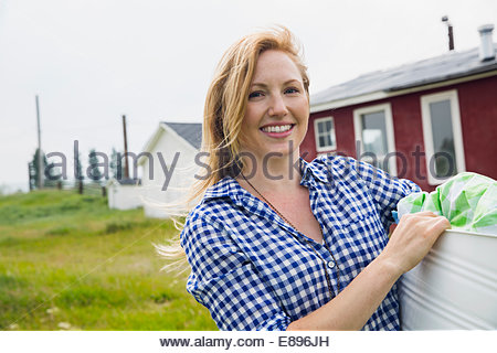 Portrait of smiling woman holding laundry outside house