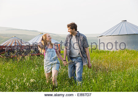 Couple holding hands and walking in rural field