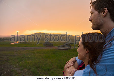 Serene couple watching sunset over rural field