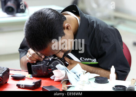 Dubai, United Arab Emirates, an employee of Canon Professional Service cleans an SLR Stock Photo